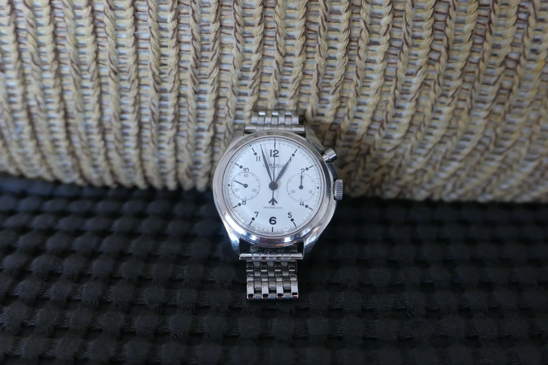 Lemania Royal Navy monopusher chronograph, white dial viewed straight-on against a wicker background